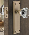 Crystal Door Knob With Long Back Plate In Waldorf And New York Style Finish on wooden door, antique brass plate visible