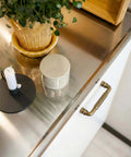 Antique Brass Fluted Cabinet Pulls, 3 Inch Hole Centers, vintage handle on white cabinet next to candle and plant