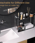Stainless steel bathroom countertop storage rack with toiletries, towels, and detachable feature, next to sink faucet.