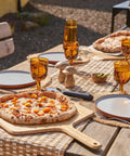 Heavy Duty 14 Inch Bamboo Pizza Peel And Wooden Spatula Paddle For Backyard Cookouts serving pizza on outdoor table.
