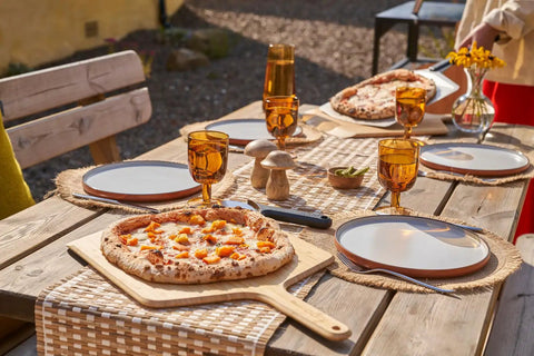 Heavy Duty 14 Inch Bamboo Pizza Peel And Wooden Spatula Paddle For Backyard Cookouts serving pizza on outdoor table.