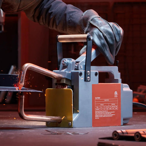 Portable 1/8 Inch Spot Welder With 1.5KVA Input Capacity in use on steel sheet, showing sparks and handheld welding gun.
