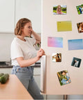 Woman using fridge with various photo magnets from DIY Fridge Magnet Making Kit 2.5 By 2.5 Inch With 100 Consumables on door