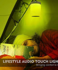 Person reading in tent with Go-To Smart Touch Bedside Lamp With Bluetooth Speaker Dimmable Color Night Light hanging above.