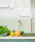 Medium Size Nail Free Wall Pegboard Organizer With Heavy Duty Hooks And Solid Wood Panel To Kick Clutter To The Curb While Freeing Up Space In Kitchen Bedroom Or Craft Room For Quick Everyday Organization on wall over a kitchen counter with fresh produce.