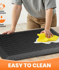 Extra Thick Four Fifths Inch Non Slip Anti Fatigue Kitchen Floor Mat Waterproof Stain Resistant Cushioned Comfort Mat For Standing And Office Use 17 By 24 Inches Black being cleaned with a cloth on a countertop