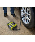 Cordless 18V Dual Function Inflator Deflator Tool for inflating car tire, shown on the ground next to vehicle on driveway
