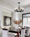 Black Farmhouse Chandelier With Six Clear Glass Shades Hanging Over Dining Table Featuring Sturdy Metal Frame And Sleek Modern Design That Hits Different For A Killer Centerpiece Vibe In Any Home Space in a stylish indoor dining area.