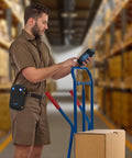 Worker uses handheld scanner with Rugged Scanner Holster Case For Handheld Barcode Scanners With Metal Belt Clip And Pen Holder, Built Tough, Compatible With TC77 TC70 TC70x TC72 TC75x TC75 MC67 M60, Black Blue, 1 Pack, in warehouse.