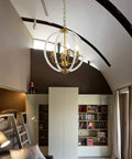Modern Four Light Pendant Chandelier with clear acrylic globes and brass finish in dope farmhouse style in a stylish living room.