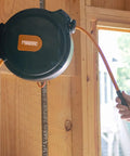Mounted compact retractable air hose reel with brass fittings and mounting bracket, visible 1/4 inch by 65 feet hybrid PVC hose.
