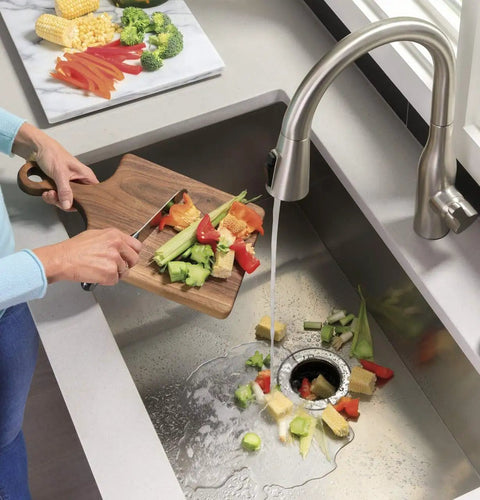 Person using Disposall Garbage Disposal With Continuous Feed 0.5 HP Motor for quick grinding of vegetable scraps.