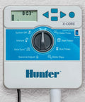 X Core XC400i Indoor Sprinkler Timer Four Zone Irrigation Controller mounted on wall, showing control panel and display.