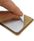 Hand peeling adhesive backing from No Sweat Top Tier 2 Inch Square Furniture Sliders with beige polyethylene glide.