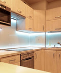 Modern kitchen featuring sleek cabinetry, minimalist design, and under-cabinet lighting with a clean, light wood finish.