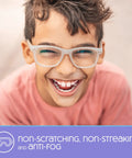 Front view of a smiling boy wearing white-framed eyeglasses; purple banner with anti-fog text.