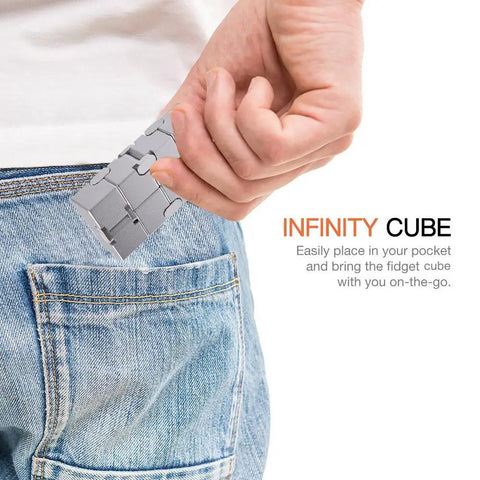 Person placing New Version Metal Infinity Cube Fidget Toy For Stress Anxiety Relief And ADHD Calming into jean pocket