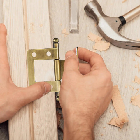 Hands installing vintage style solid metal cabinet door hinge 19mm non mortise folding hinge on wooden surface with tools nearby