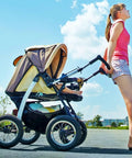 Woman pushing a stroller on a sunny day, showcasing stroller wheels that use 12 Inch Bike Inner Tubes For 12x1.75 12x1.90 12x1.95 12x2.0 12x2.10 12x2.125 With AV32mm Schrader Valve 2 Pack Fits Road Mountain And Kid Bikes Durable Butyl Tubes.