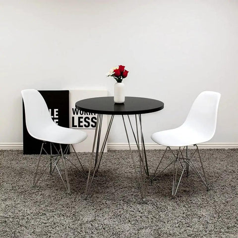 Modern round table with two white chairs on a gray carpet in a minimalist room with art decor and flowers on the table.
