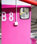 Wide Angle Safety Convex Mirror Rock Solid Wall Mount For Garage Warehouse Parking Lot Crushes Blind Spots And Keeps You Covered With No Fuss Easy Install Setup mounted on pink wall in parking garage.
