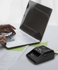 Portable Counterfeit Money Detector With LCD Display, Infrared And Magnetic Detection, next to laptop, verifying bill