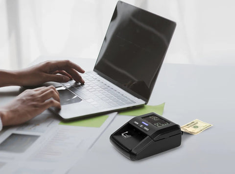 Portable Counterfeit Money Detector With LCD Display, Infrared And Magnetic Detection, next to laptop, verifying bill