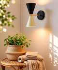Mid-Century Two-Tone Cone Wall Sconce Light - Black & White Dual Funnel Wall Mounted Lamp with Gold Accent Ring - Up and Down Wall Lighting Fixture for Living Room & Bedroom illuminating a cozy corner with a plant.