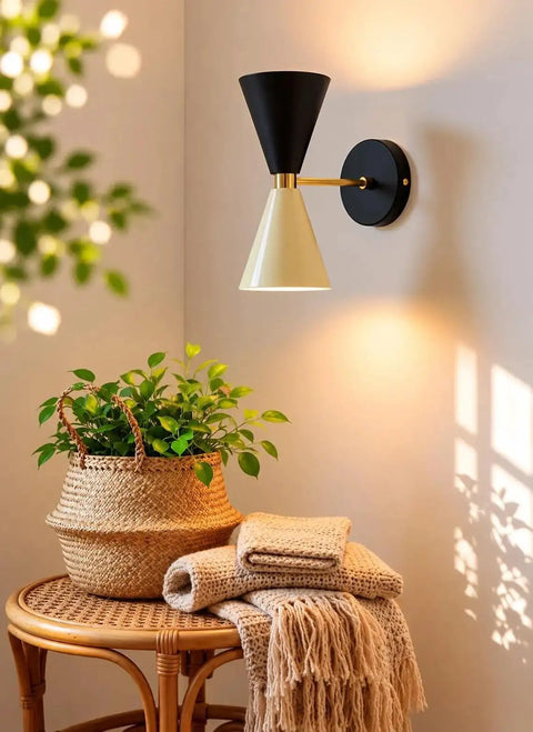 Mid-Century Two-Tone Cone Wall Sconce Light - Black & White Dual Funnel Wall Mounted Lamp with Gold Accent Ring - Up and Down Wall Lighting Fixture for Living Room & Bedroom illuminating a cozy corner with a plant.