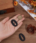 Hand holding 2 Pcs Black Oval Brass Sword Seppa Spacers For Japanese Samurai Swords Replacement 1.7 Inch By 1 Inch Washers