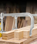 Heavy Duty Large Steel Ratcheting F Clamp For Welding Woodworking Metal Fabrication on wooden beams, showcasing durable grip construction.