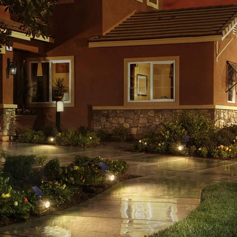 Outdoor Solar Spotlight Kit With 18 LED Ultra Bright Lights illuminating a garden path at night by a house.