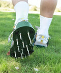 Person walking on grass wearing lawn aerator shoes for grass health with adjustable straps and heavy duty spikes one size fits all