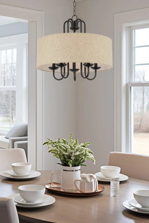 Gwenyth 20 Inch Modern Farmhouse 5 Light Drum Chandelier With Oatmeal Linen Shade Rustic Arched Metal Hanging Fixture In Oil Rubbed Bronze Finish For A Warm Cozy Dining Room Vibe hanging over dining table.