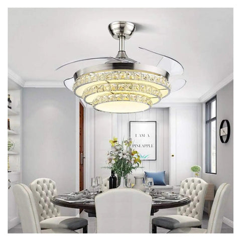 42 Inch Retractable Blade Ceiling Fan Featuring Glowing Crystal Chandelier And Smart Remote Controls For Tunable Led Lights In A Legit Bedroom Or Dope Living Room Vibe over a dining table in a modern setting.