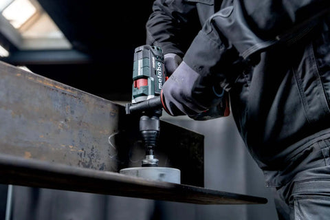 Close-up of Tough As Nails 18V Cordless Power Drill With Supra SK Drill Chucks working on steel during heavy drilling.