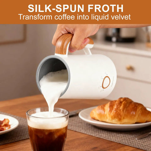 Pouring foam from Powerful 4 In 1 Electric Milk Frother And Warmer With Dual Whisks into coffee with croissant nearby on table.