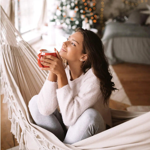 Person relaxing in a Boho Macrame Hammock With Elegant Tassels For Patio And Yard Cozy And Chill For Indoor Or Outdoor Use 450 Pound Capacity
