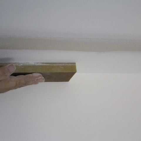 Hand using Extra Large Drywall Sanding Sponge With Fine And Medium Grits for rough and finish sanding on ceiling surface.