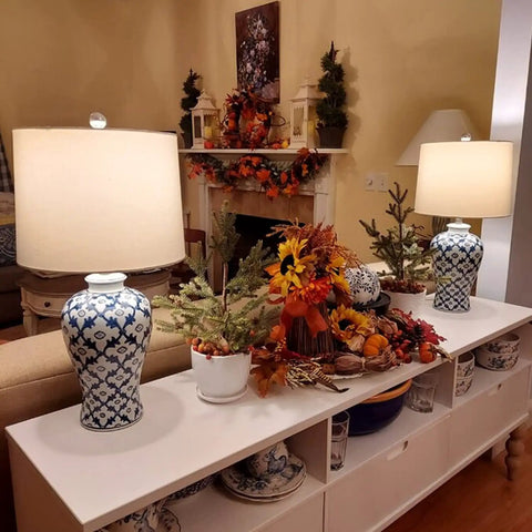 Blue Ceramic Table Lamp With White Fabric Shade Chinoiserie Urn Style Hand Painted Detail alongside autumn decor on a sideboard