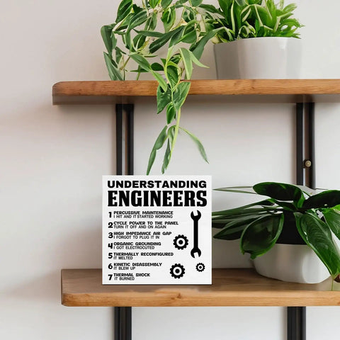 Funny Engineering Desk Sign for Engineers, Developers, Mechanics, Home Office Decor on wooden shelf with plants, 5x5 inch plaque