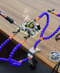 No Hands Soldering Clamp Aid With Four Alligator Clips Wire Clip Holder in use for circuit board soldering on wooden table
