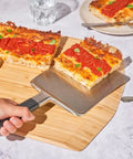 Heavy Duty 14 Inch Bamboo Pizza Peel And Wooden Spatula Paddle For Backyard Cookouts Smooth Launch Slide Design, lifting a slice.