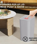 Three Pack 10L Small Trash Cans With Lids Pop Up Lid in grey showcased in living room with person's hand pressing lid