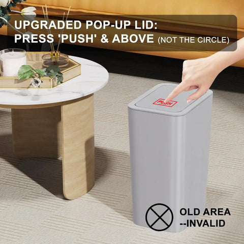 Three Pack 10L Small Trash Cans With Lids Pop Up Lid in grey showcased in living room with person's hand pressing lid