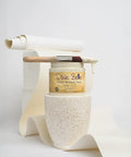 Drop Cloth Chalk Mineral Paint For Furniture In Matte Linen White 16 Oz with paintbrush on a textured surface