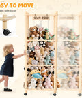 Child pushing extra large stuffed animal zoo organizer with wheels for kids rooms, filled with plush toys and labeled 'Our Zoo'.