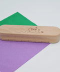 Wooden Clapper Tool For Pro Sewing And Quilting Nine Point Five Inch Hardwood Ironing Clapper on colored fabric squares