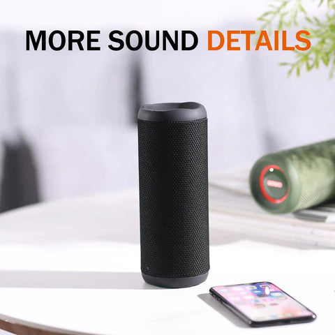 Wireless Portable Speaker With 25W Bangin Bass And Bassboom Technology IPX7 Waterproof Bluetooth Speaker TWS Pairing Built In Mic 16 Hour Playtime With Lights For Home And Outdoor Fun on table next to smartphone