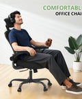 Person relaxing in an ergonomic desk chair for long hours with high back and plush lumbar support, flip up armrests, rolling swivel, black.